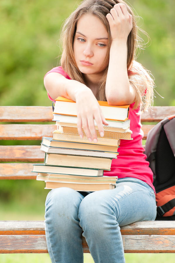 sad-young-student-girl-sitting-bench-books-20733967